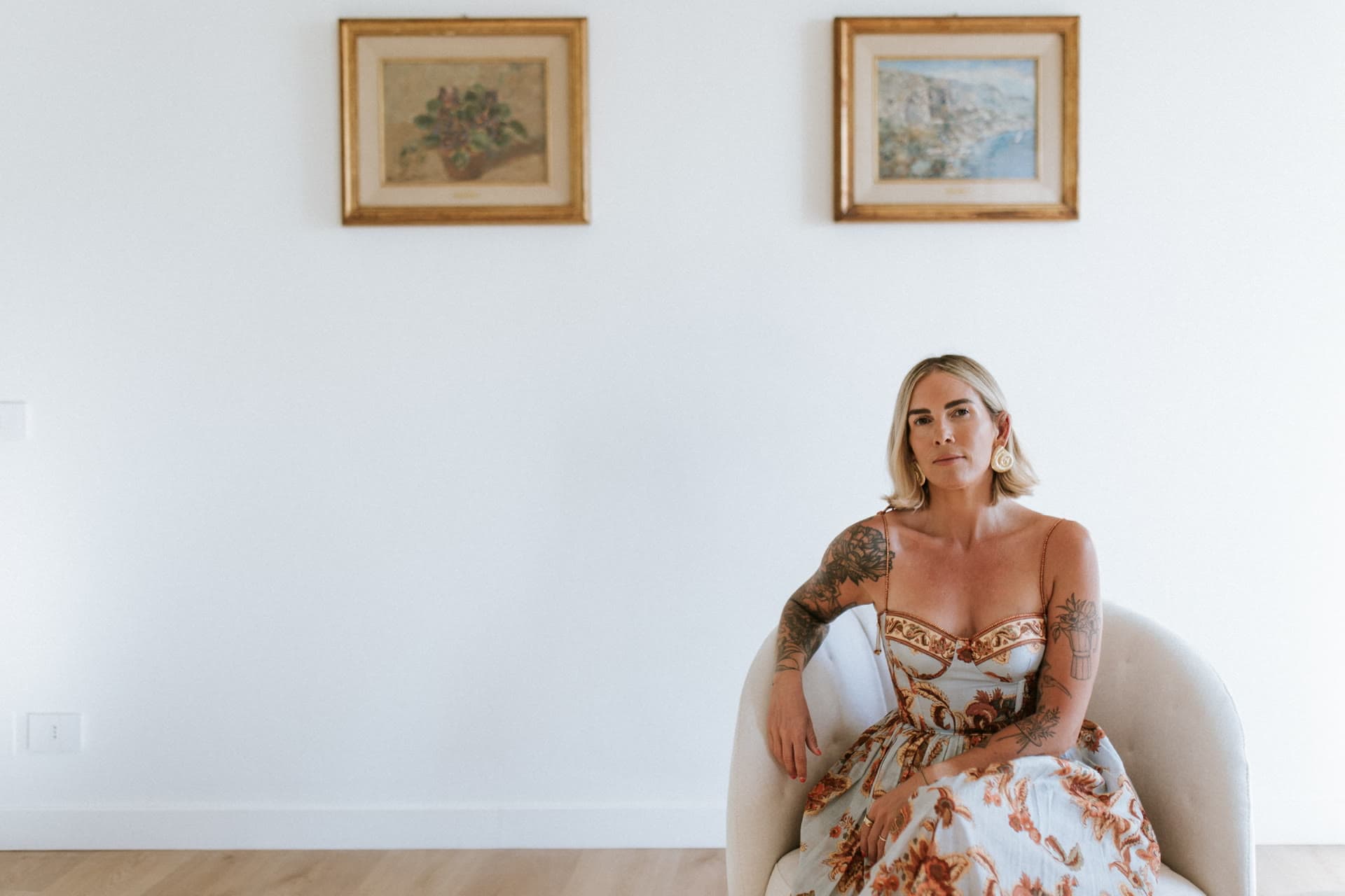 Kat seated beneath two framed paintings in the Lula Mare living room