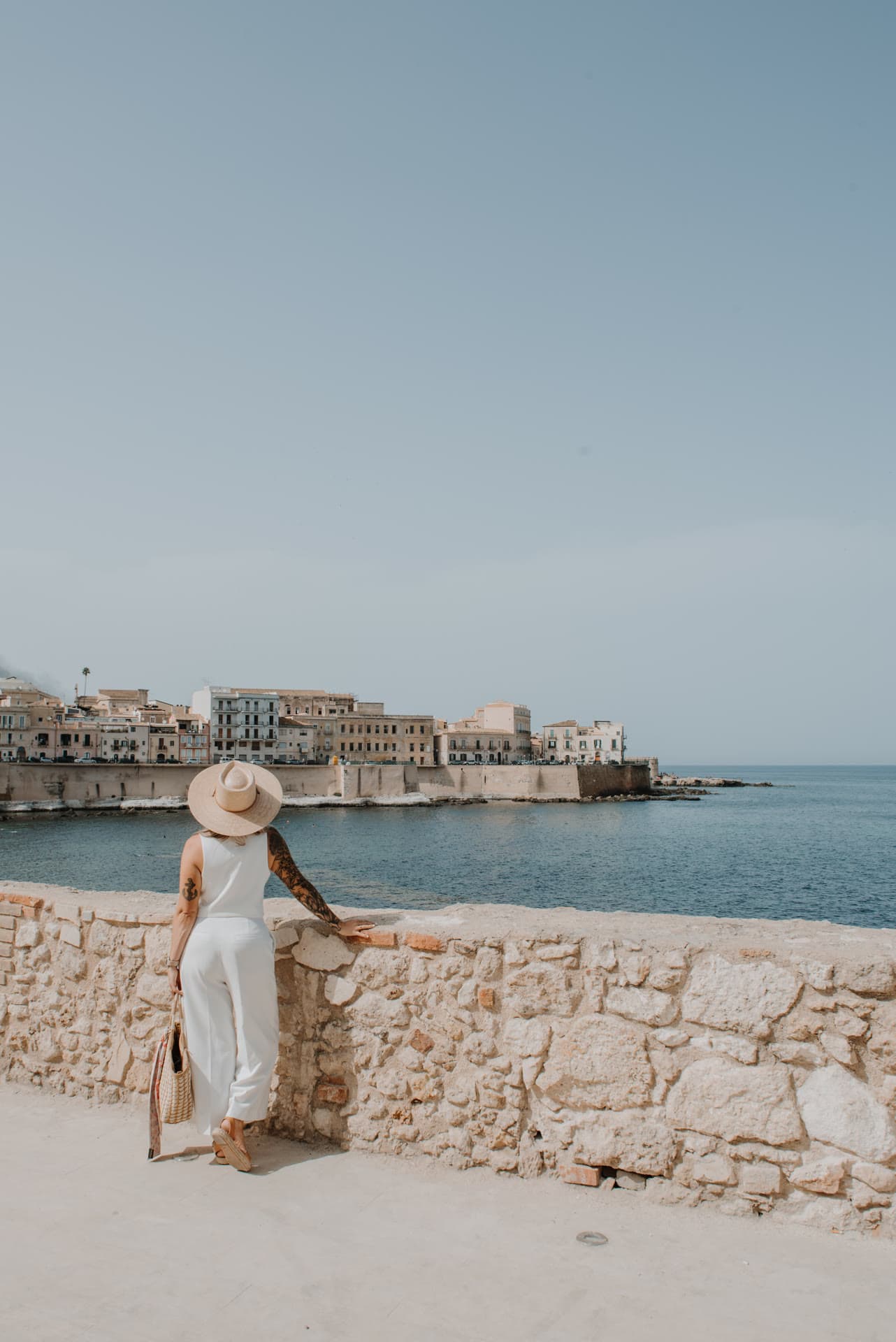 Kat in a sunhat looking out over the Ortigia skyline and the sea