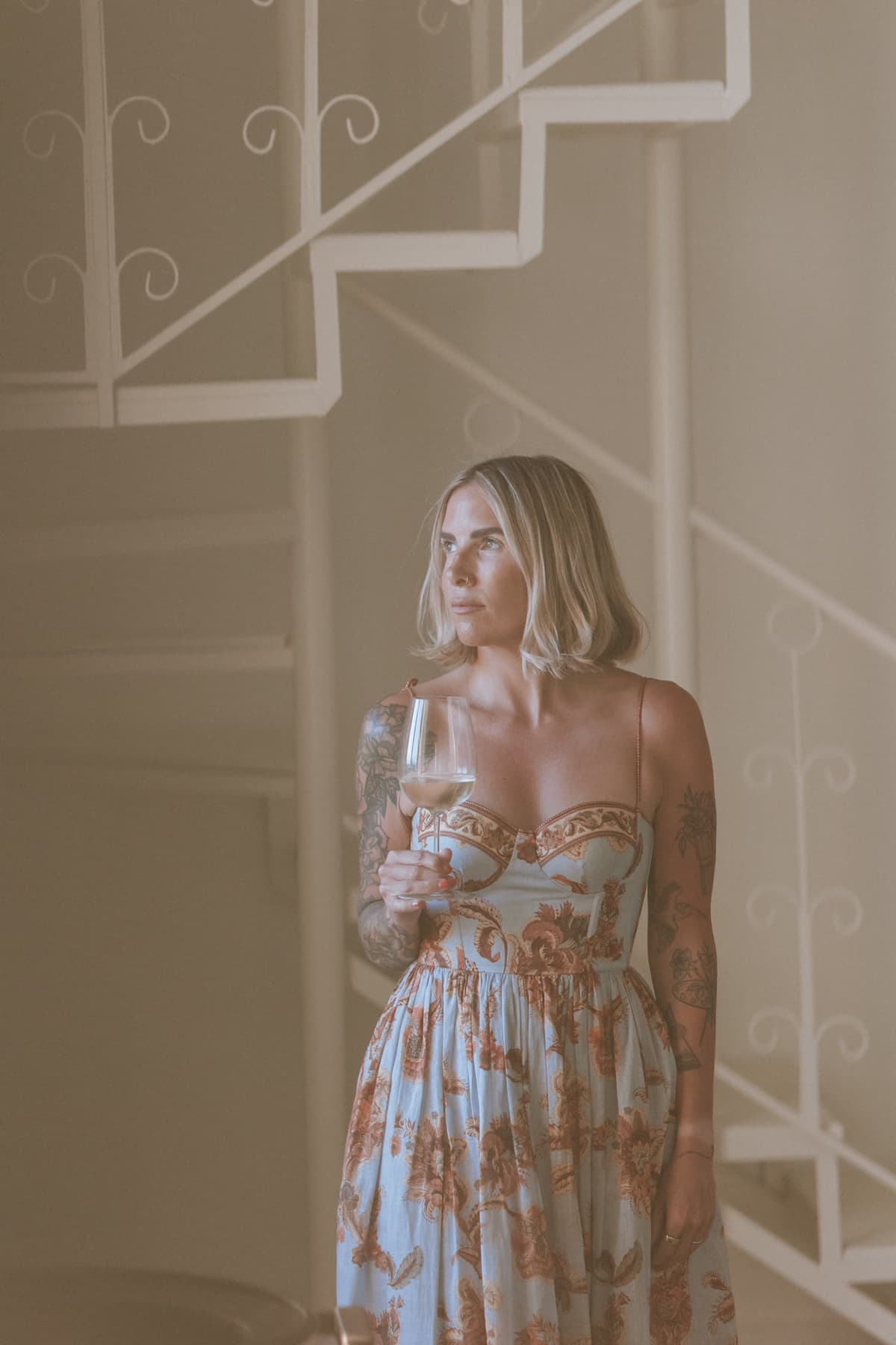 Kat with a glass of wine beside the white spiral staircase at Lula Mare